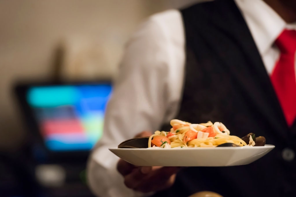Close up photo of male waiter holding plate with food at the restaurant, selective focus